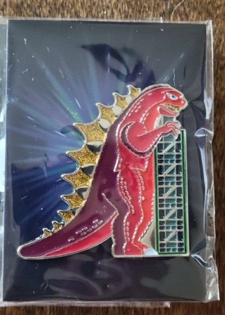 Red Godzilla enamel pin on starburst backing card in protective plastic